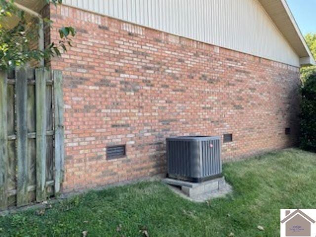 view of side of home featuring central AC unit and a yard