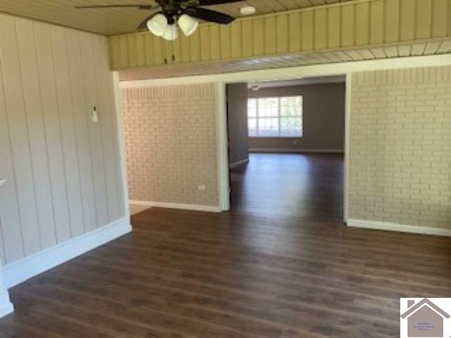 unfurnished room with wood walls, ceiling fan, and dark hardwood / wood-style floors