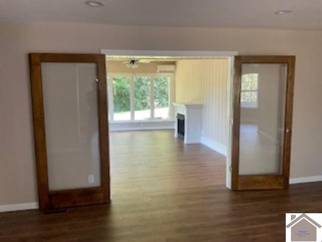 hallway with dark wood-type flooring and a wall unit AC