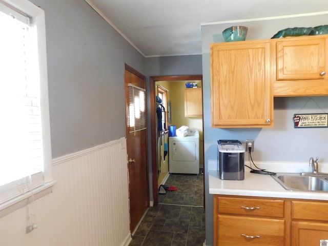 kitchen with sink, dark tile patterned flooring, washer and dryer, and a wealth of natural light