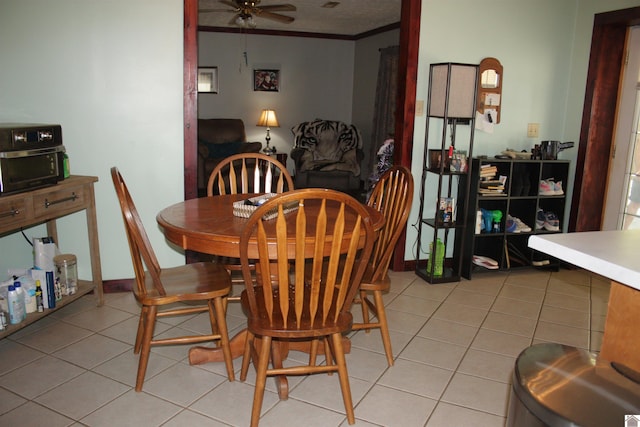 tiled dining area with ornamental molding and ceiling fan