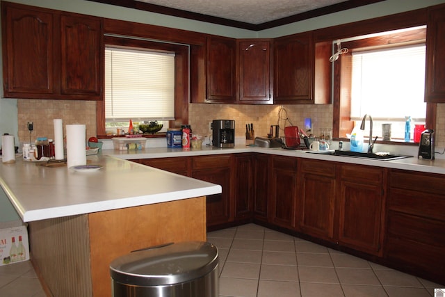 kitchen with light tile patterned floors, kitchen peninsula, sink, and decorative backsplash