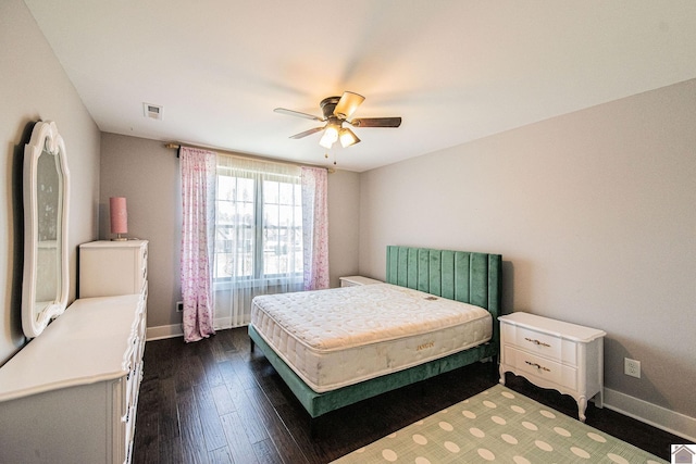 bedroom featuring baseboards, visible vents, dark wood finished floors, and a ceiling fan