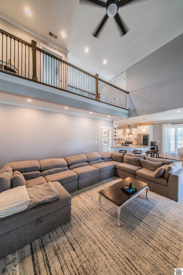 living room with ceiling fan and a towering ceiling