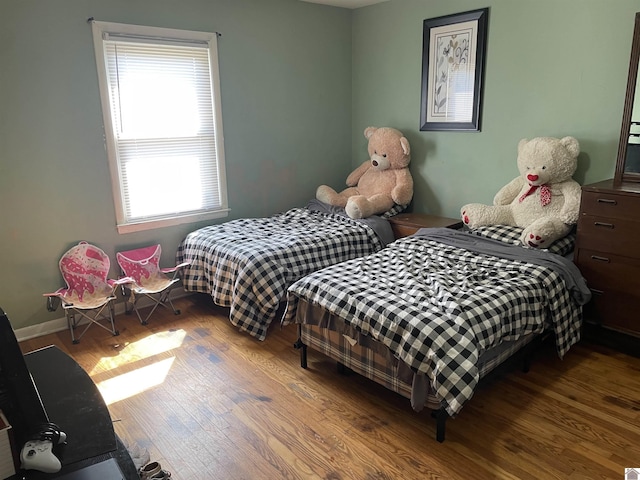 bedroom with multiple windows, baseboards, and wood finished floors