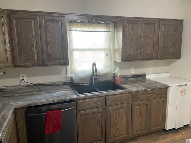 kitchen featuring dishwasher, a sink, and wood finished floors