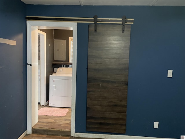 laundry area featuring washer / clothes dryer, a barn door, wood finished floors, laundry area, and electric panel