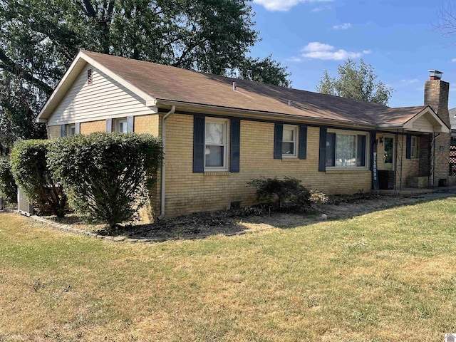 view of side of property featuring brick siding, a yard, and a chimney