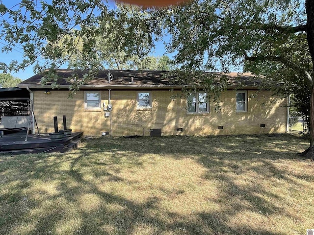 back of property featuring crawl space, brick siding, and a yard