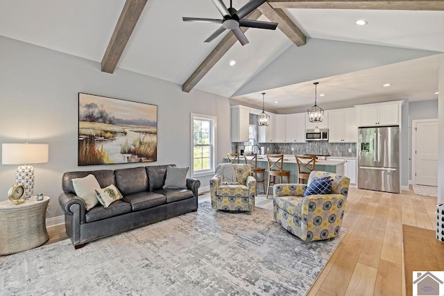 living room featuring ceiling fan with notable chandelier, high vaulted ceiling, beam ceiling, and light hardwood / wood-style floors