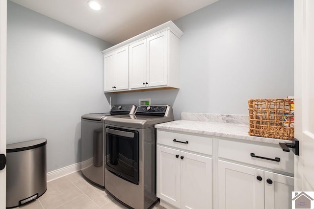 washroom with light tile patterned floors, cabinets, and washing machine and clothes dryer