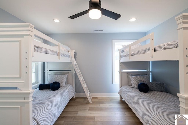 bedroom featuring ceiling fan, multiple windows, and hardwood / wood-style flooring