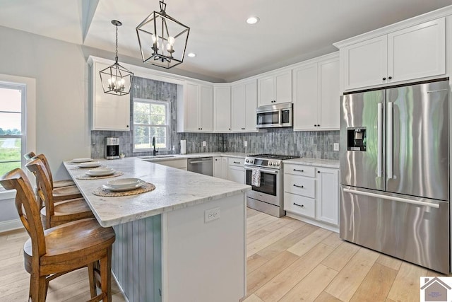 kitchen featuring a kitchen bar, stainless steel appliances, backsplash, and light hardwood / wood-style floors