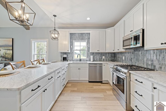 kitchen featuring a healthy amount of sunlight, light wood-type flooring, appliances with stainless steel finishes, and tasteful backsplash