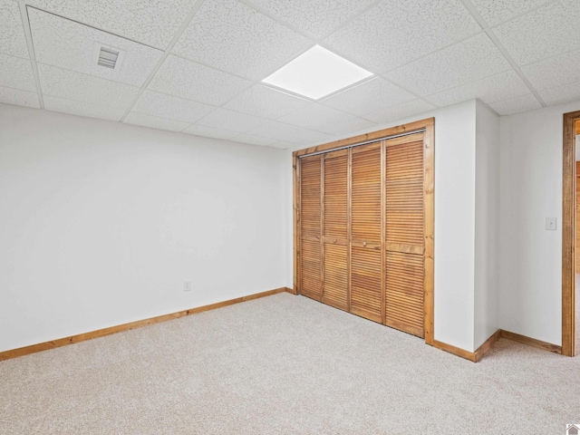 unfurnished bedroom featuring a closet, carpet floors, and a drop ceiling