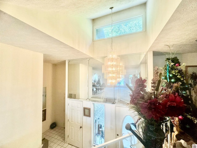 interior space with a chandelier, a textured ceiling, and tile patterned flooring