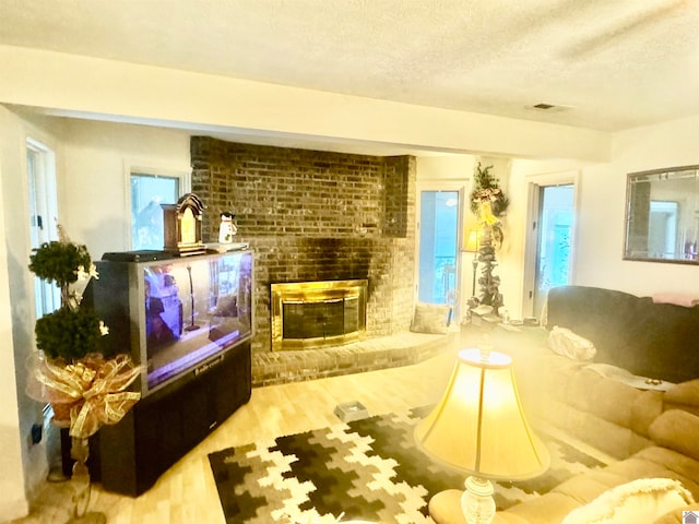 living room featuring wood-type flooring, a textured ceiling, and a fireplace