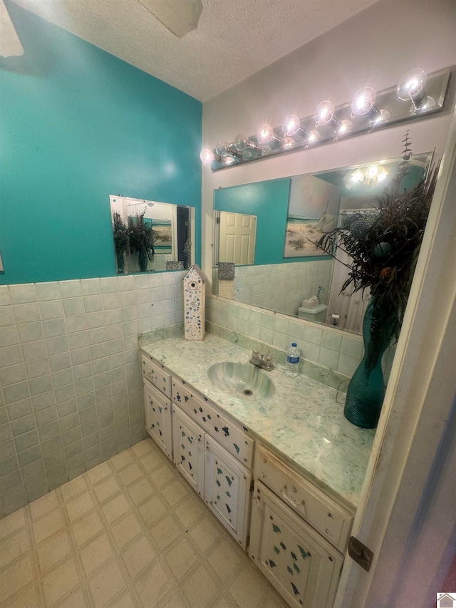 bathroom with tile walls, vanity, and a textured ceiling