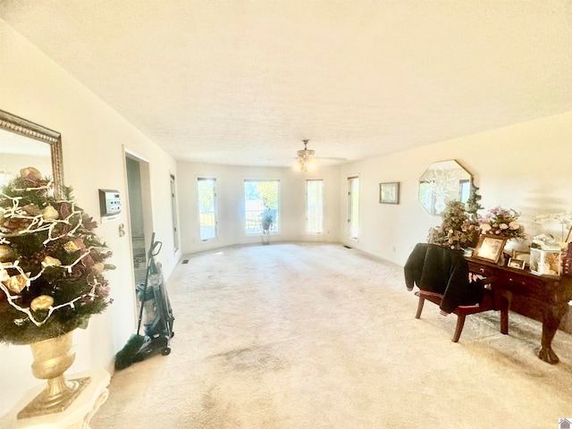 living room featuring ceiling fan, a textured ceiling, and light colored carpet