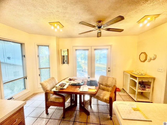 tiled dining space with a textured ceiling and ceiling fan