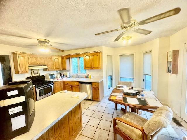 kitchen featuring ceiling fan, a textured ceiling, light tile patterned flooring, sink, and stainless steel appliances