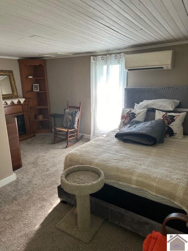 bedroom with a wall mounted AC, carpet flooring, wood ceiling, and crown molding