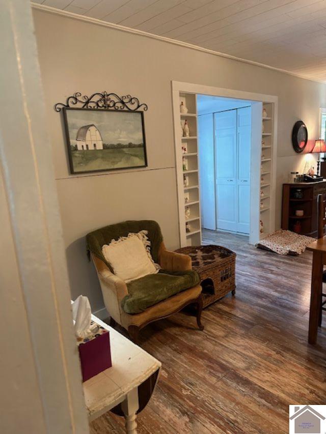 living area with ornamental molding, hardwood / wood-style floors, and wooden ceiling