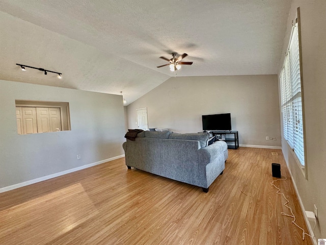 living room with a textured ceiling, vaulted ceiling, light hardwood / wood-style floors, ceiling fan, and track lighting