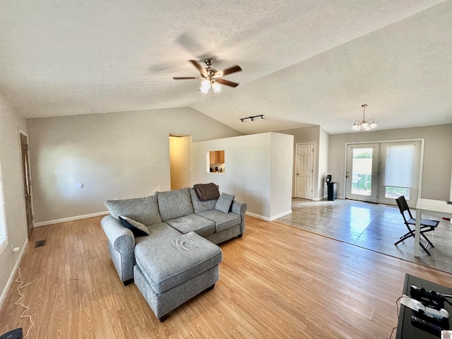 living room featuring ceiling fan with notable chandelier, a textured ceiling, french doors, vaulted ceiling, and light hardwood / wood-style floors