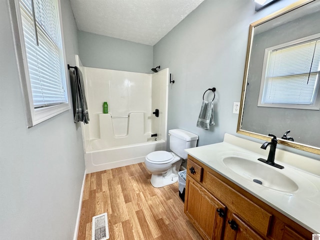 full bathroom featuring shower / bathtub combination, hardwood / wood-style floors, toilet, vanity, and a textured ceiling