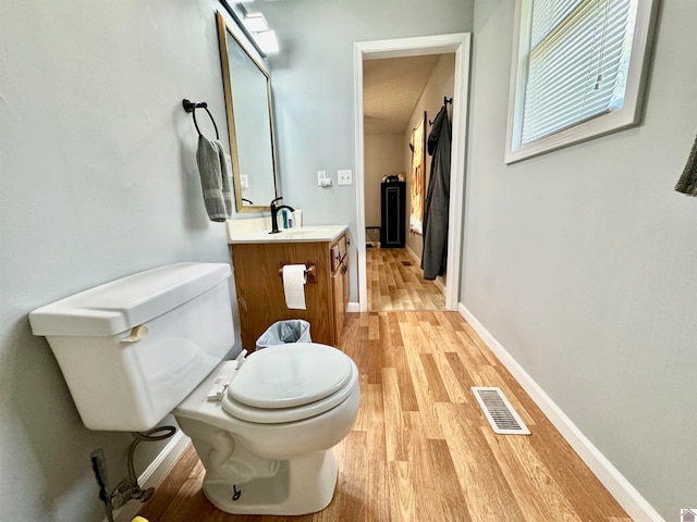 bathroom with vanity, toilet, and hardwood / wood-style flooring