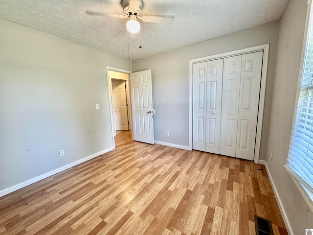 unfurnished bedroom with a textured ceiling, ceiling fan, a closet, and light hardwood / wood-style floors