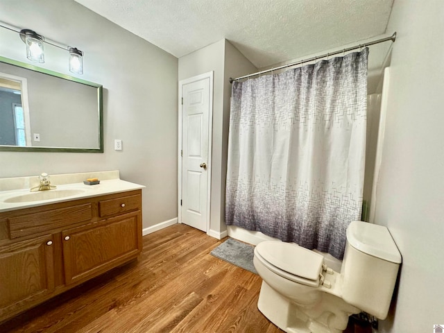 bathroom with a textured ceiling, vanity, toilet, a shower with curtain, and hardwood / wood-style flooring