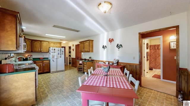 kitchen with a textured ceiling, wood walls, sink, and white appliances