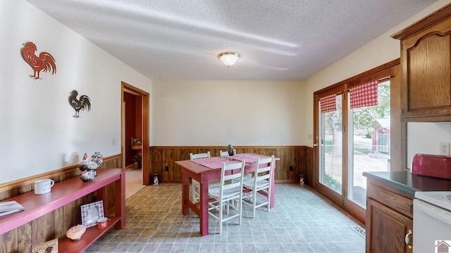 dining space featuring a textured ceiling and wood walls