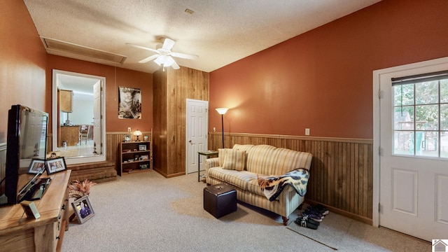 sitting room featuring carpet flooring, wood walls, and ceiling fan