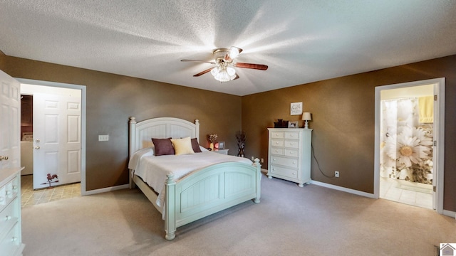 bedroom with ceiling fan, connected bathroom, light carpet, and a textured ceiling