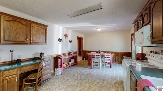 kitchen featuring white appliances, wooden walls, and a textured ceiling