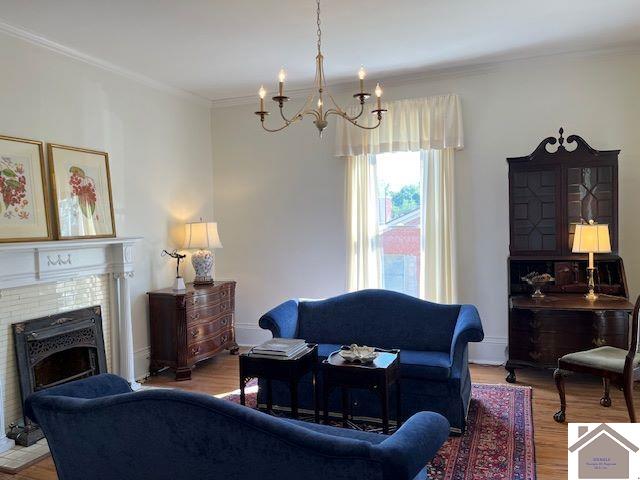 living room with wood-type flooring, a chandelier, and ornamental molding