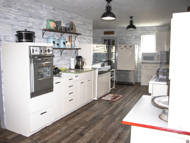 kitchen featuring decorative light fixtures, dark hardwood / wood-style flooring, white appliances, and white cabinetry