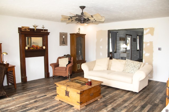 living room featuring ceiling fan, a textured ceiling, and dark wood-type flooring