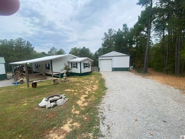 view of front of house with a fire pit, an outdoor structure, a garage, and a front yard