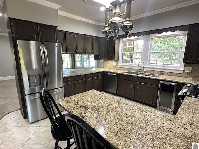 kitchen featuring decorative backsplash, light stone counters, appliances with stainless steel finishes, ornamental molding, and a sink