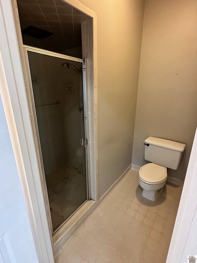 bathroom with a shower stall, toilet, and baseboards