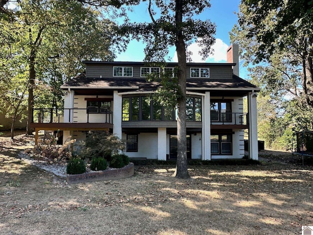 back of house featuring a chimney and a balcony