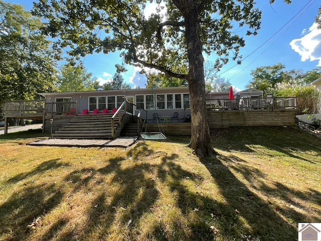 rear view of house featuring a wooden deck and a lawn