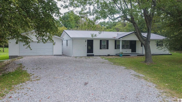 ranch-style home with gravel driveway, a front lawn, metal roof, a garage, and an outdoor structure