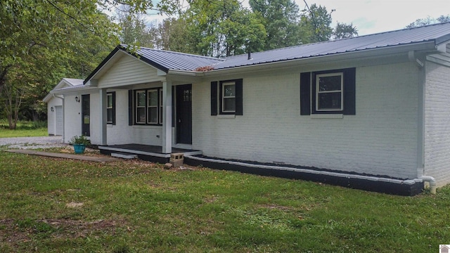 single story home with brick siding, a garage, metal roof, and a front lawn