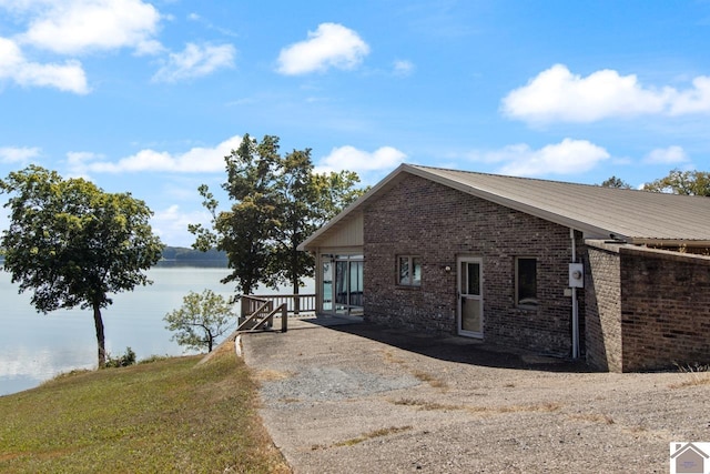 view of side of home featuring a lawn and a water view