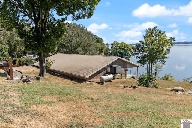 view of property exterior with a water view, a yard, and an outbuilding